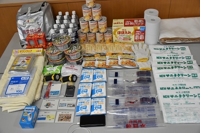 非常用持ち出し袋や常備水などの防災グッズが写真で置かれている様子