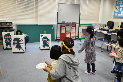 こども忍者道場で忍者絵が書かれた的に向かって手裏剣を投げる遊びをしている児童たちの写真