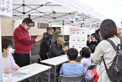 手話体験で講師のお手本と絵を見ていろいろな手話に挑戦する児童たちの写真