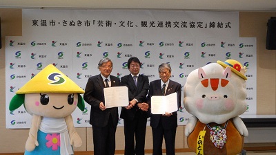 締結式の会場で東温市とさぬき市の両市長とマスコットキャラクターが協定書を手に、並んで記念撮影をしている写真