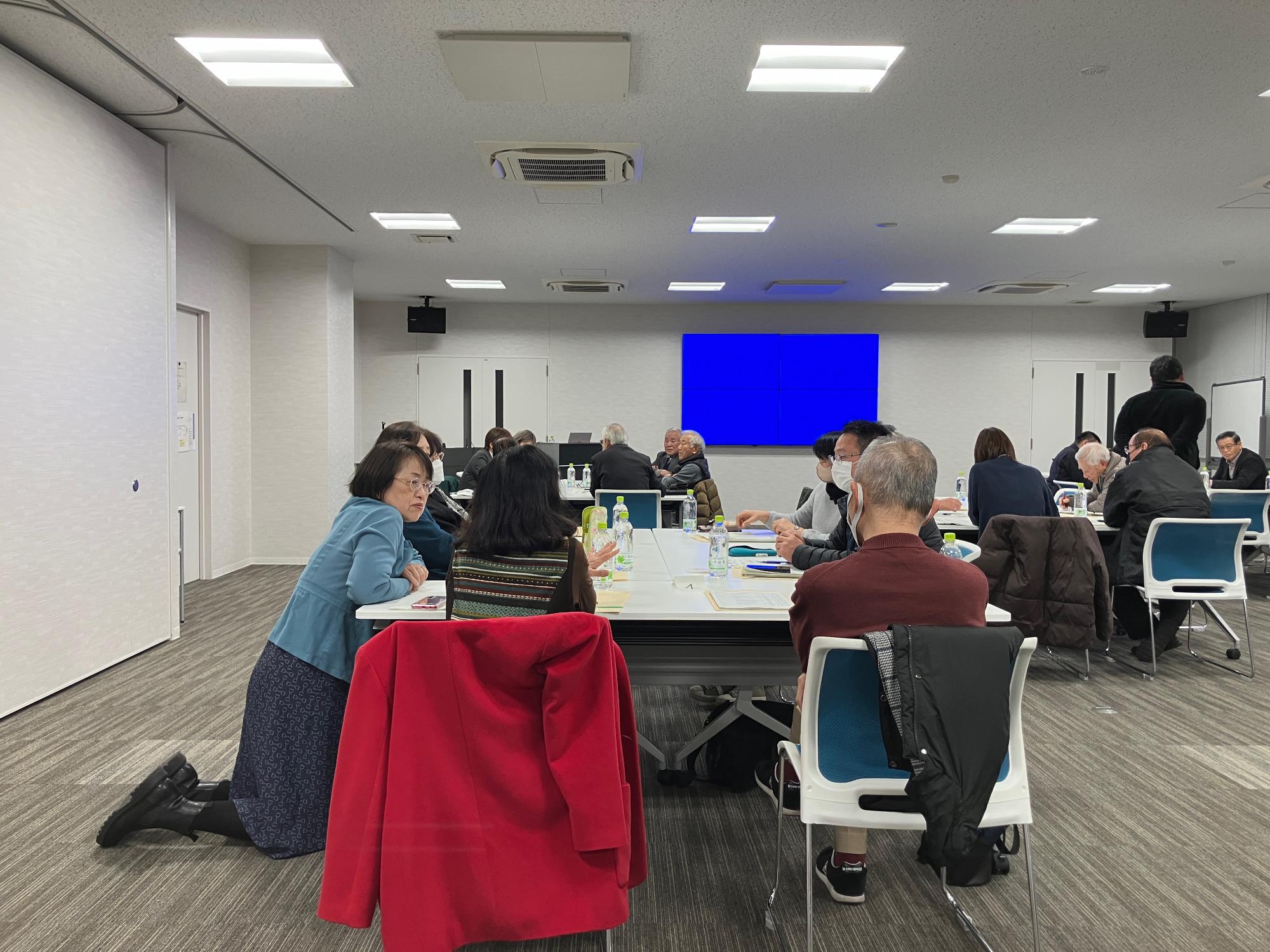 会議室にて参加者とグループワークを行うファシリテーターの女性の写真