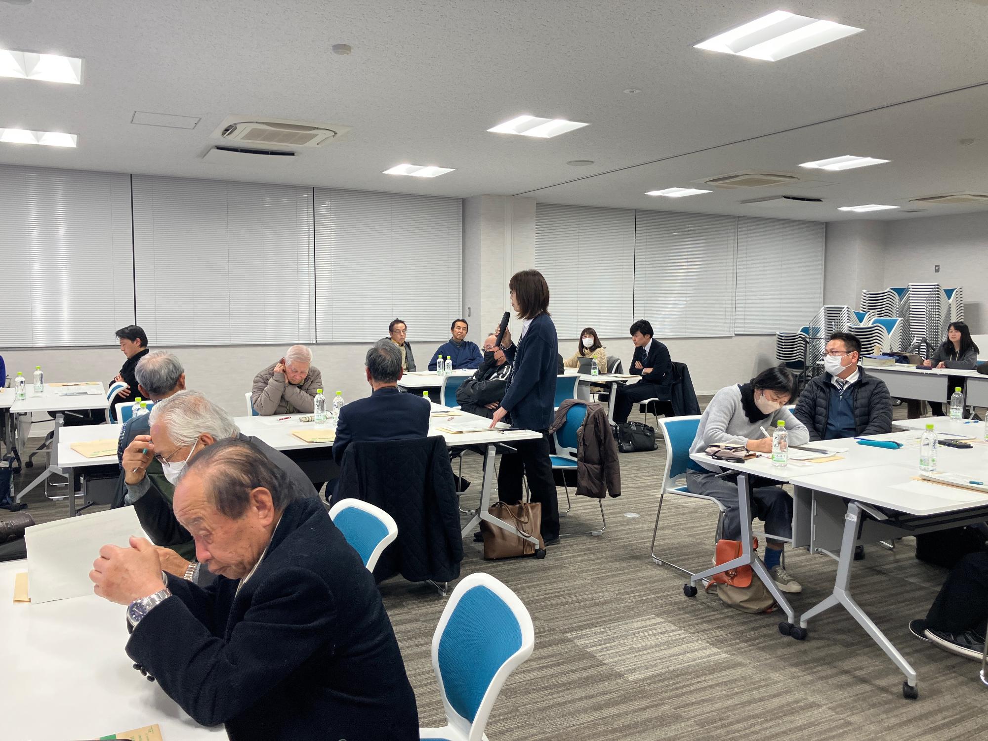 会議室にてグループワークで出た意見を発表する女性の写真