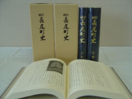 背表紙に改訂長尾町史と書かれた4冊の本の手前にの開かれた本が置かれた写真