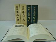 背表紙に新編志度町史と書かれた4冊の本の手前にの開かれた本が置かれた写真