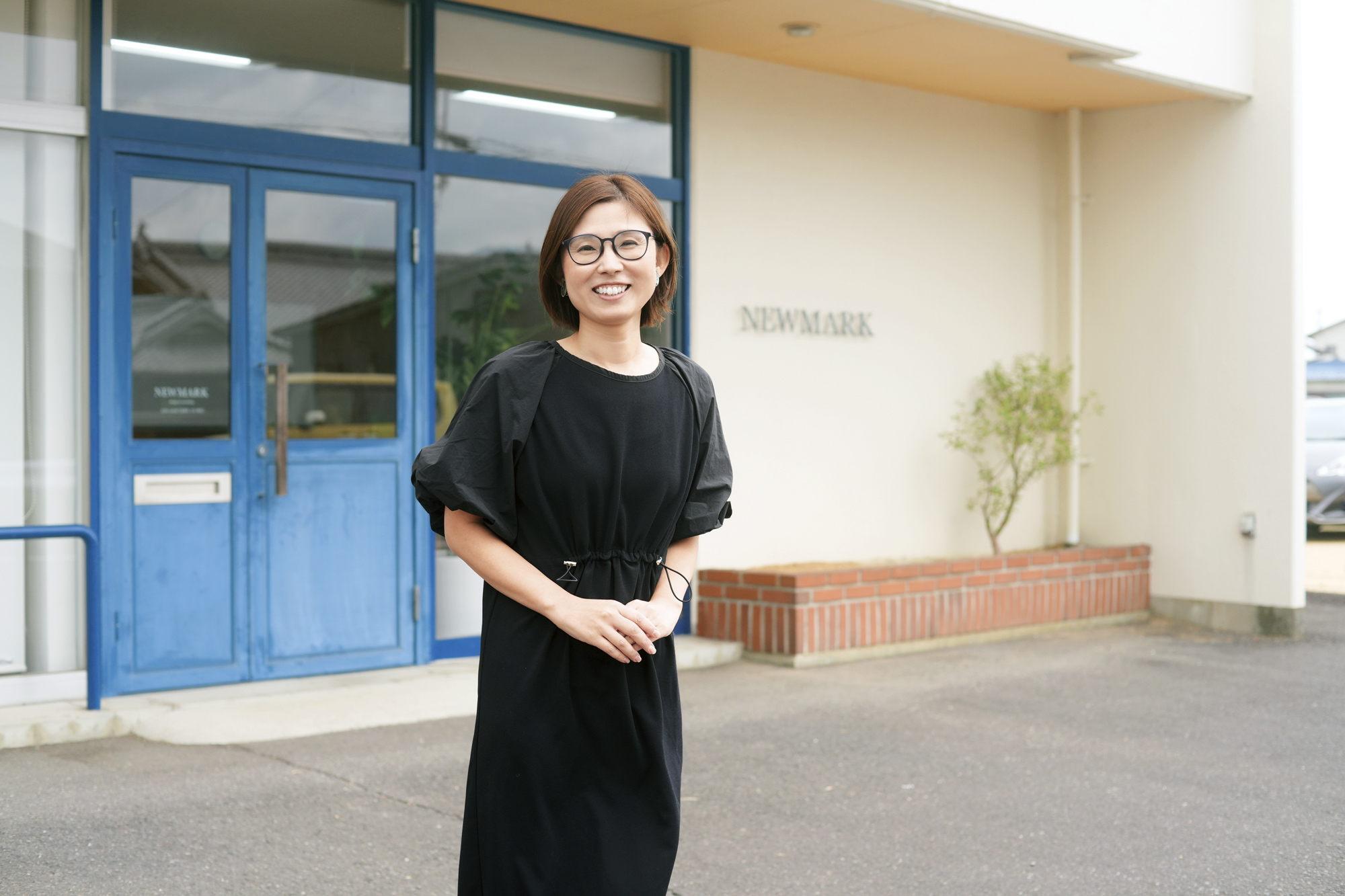 会社の前で笑顔で立つ末次さん