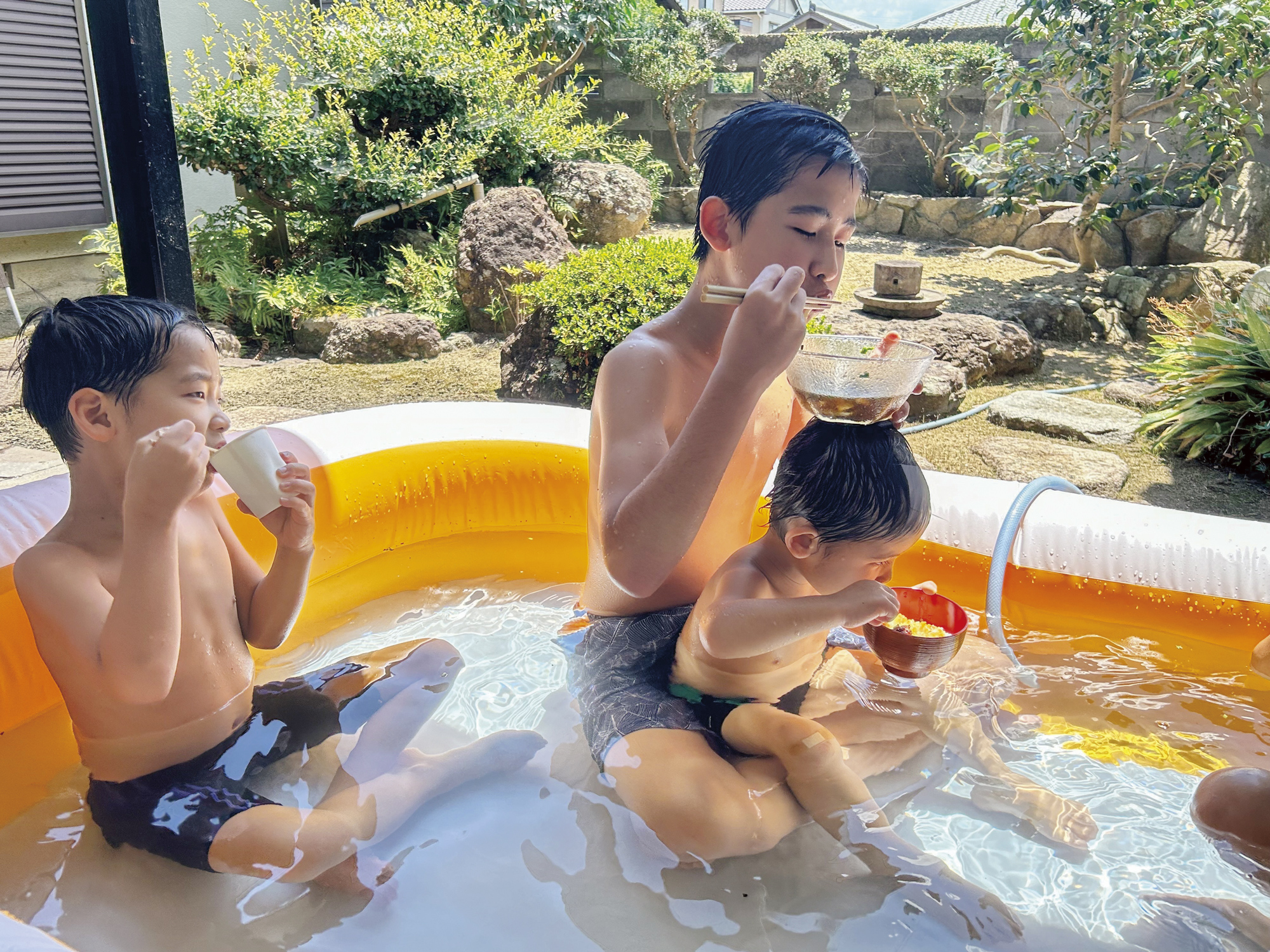 3人の子どもがビニールプールに入っている