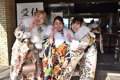 左右の二人がピース、中央の一人が片手で丸を作るポーズをする3名の振り袖姿の女性