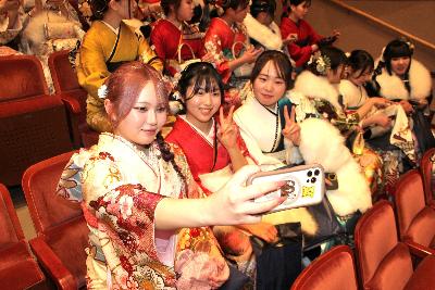 会場内の席に座りながら自撮りする3名の振り袖姿の女性