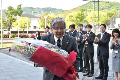 職員から受け取った花束を手に初登庁する大山市長