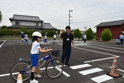 横断歩道を渡るために停止している男性と自転車に乗った女子児童