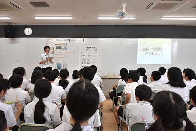 市選管の職員が開票結果を報告し、それを聞く児童たち