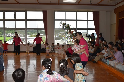 保護者に見守られながら、先生と一緒に盆踊りを踊る子どもたち