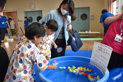 保護者と一緒に金魚すくいを楽しむ子どもたち