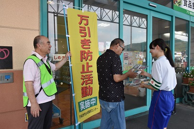 フジ志度店の入り口で来店客に啓発グッズを手渡す中学生と補導員
