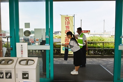フジ志度店の入り口で啓発グッズを手渡す中学生と補導員