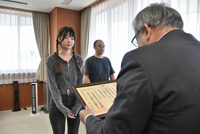 感謝状を受け取る女性店員と、隣に立つ男性店員