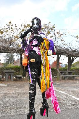 振り返りながらポーズをとる狐のお面を被ったオリジナルキャラに扮するコスプレイヤー