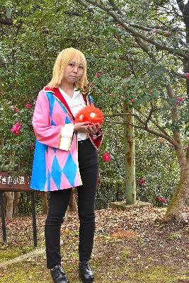 椿の木の近くでカルシファーを抱えたハウルに扮するコスプレイヤー