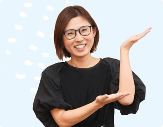 両手を広げて案内するようなポーズをとる、笑顔の移住者女性