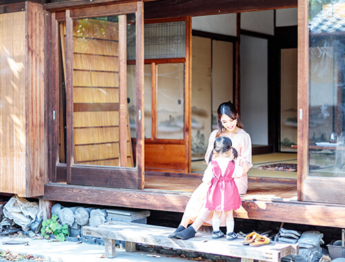 古民家の縁側に座り、子どもと触れ合う女性