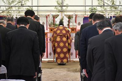 宮司とスーツ姿の関係者が祭壇に拝礼する様子