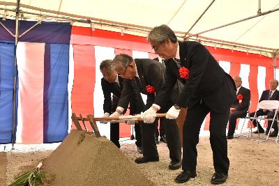 市長、議長、教育長が盛られた土に鍬を入れる様子