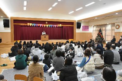 壇上の宮下園長の話を座って聞く園児と保護者