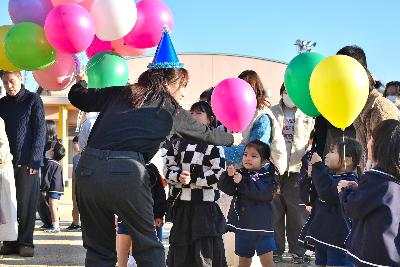 園庭でバルーンリリースに使うバルーンを先生から手渡しされる園児たち