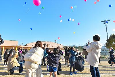 バルーンリリースで放った風船を見上げたり写真を撮ったりする園児や保護者の様子