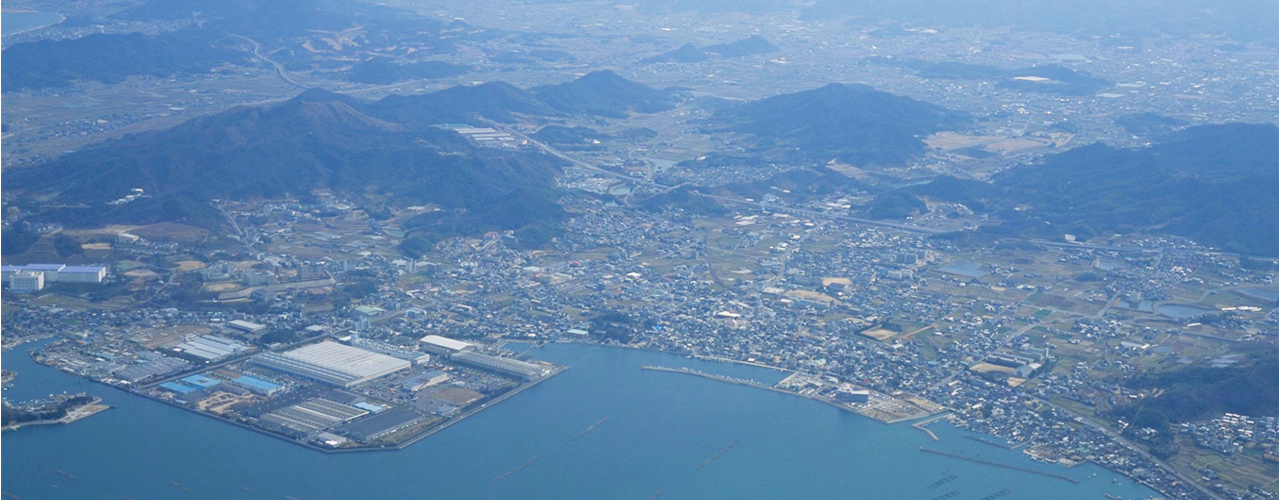 海に面した街並みと山々を望む、広大な空撮風景