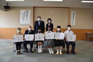 表彰状が授与された方々が表彰状を胸の前あたりに広げて撮影された集合写真