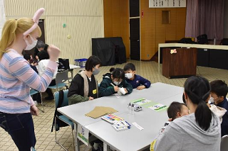 真剣にバニーバック作りをする女児とその様子をのぞき込む男児の写真