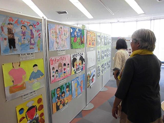 パネル展に展示された色とりどりのポスターを眺める訪問者たちの写真