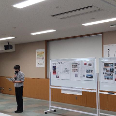 男女共同参画社会につながる活動に取り組んだ市民の報告として男性がホワイトボードに資料を広げて報告している写真