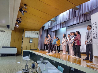 舞台上から紙飛行機の飛距離を競うイベントを行っている写真