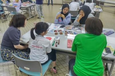 テーブルに広げられた写真を見ながら談笑しているグループの写真