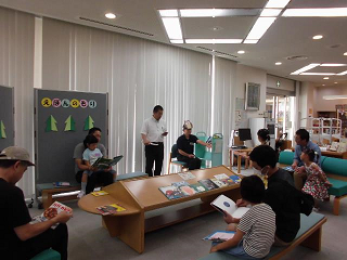 お父さんが子どもを膝の上に抱え、一緒に絵本を開いて読み聞かせをしている写真