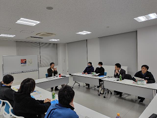 参加者たちがロの字に配置されたテーブルを囲んで話し合っている写真