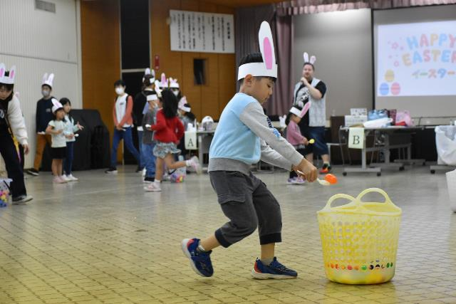 男の子がスプーンリレーでスプーンの上から卵をケースに入れている瞬間の写真