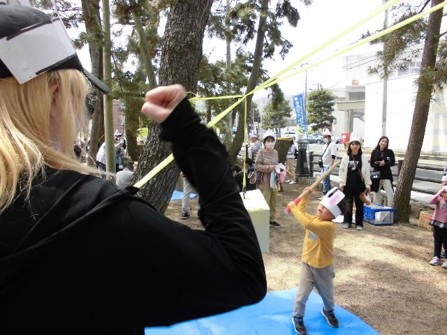 手作りくす玉を割るピニャータでバニーヘッドバンドを目隠しにして挑戦している児童の写真