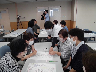 参加者たちが各テーブルに分かれ「家の危険個所など」について話し合っているグループワークの写真