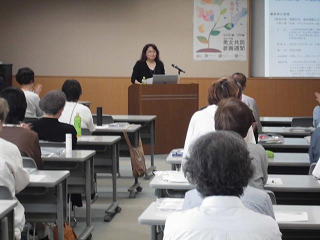 演壇から、自身が取り組んだ男女共同参画社会につながる活動について報告する女性の写真