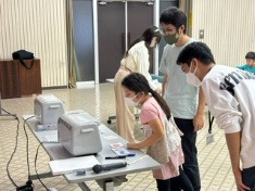 作成したキーホルダーをオーブンで焼いて固めている様子を見る女児の写真