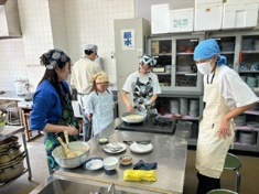 三角巾とエプロンを付けて伝統のお菓子作りに挑戦する参加者たちの写真