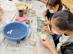 真剣な様子で干支の陶芸品に色付けをしている女性二人の写真