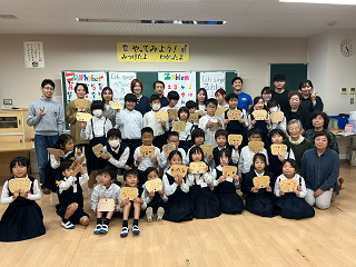子ども達がそれぞれ書いたうちわ型のお手紙を胸元に掲げて撮影した集合写真