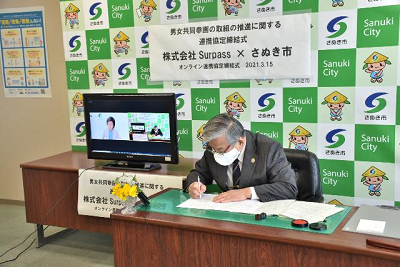 オンラインでの男女共同参画の取組の推進に関する協定書にサインするさぬき市長の写真