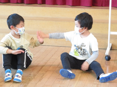 ホールで2人の男の子が座ってハイタッチをしている写真