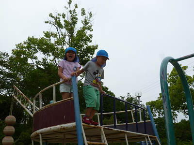 水色の帽子を被った2人の園児が屋外の遊具で遊んでいる様子の写真