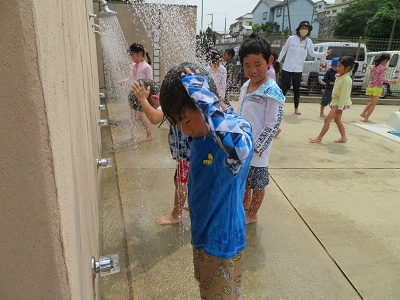 プール横のシャワーで子どもたちが水を浴びて体を洗っている様子の写真